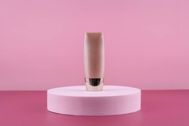 Bej kapatıcı temel kozmetik ürünleri pembe arka planda taklit ediliyor. Kozmetik sıvısı vakfı çıplak krem şişesi podyum kaidesi üzerinde. Cilt bakımı, pansiyon düzelticisi.