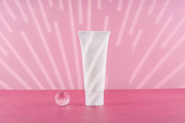 Maqueta de tubo de plástico blanco crema cosmética sin marca sobre fondo rosa con accesorios elegantes. Embalaje de productos de belleza para el cuerpo y la salud en blanco. Botella de crema hidratante para manos. — Foto de Stock