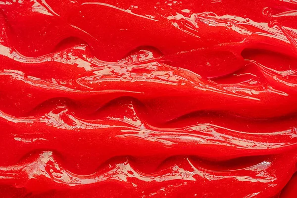 Red gel texture. Cosmetic clear liquid cream smudge. Skin care product sample closeup. Toothpaste or wax — Stockfoto