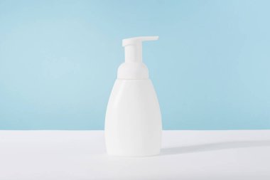 Banyo sabunu beyaz kozmetik şişe maketi mavi arka planda. Vücut bakım ürünü veya losyon ambalajı. Plastik kozmetik tüpü ön görünüm reklam modeli. Vücut hijyen kremi.