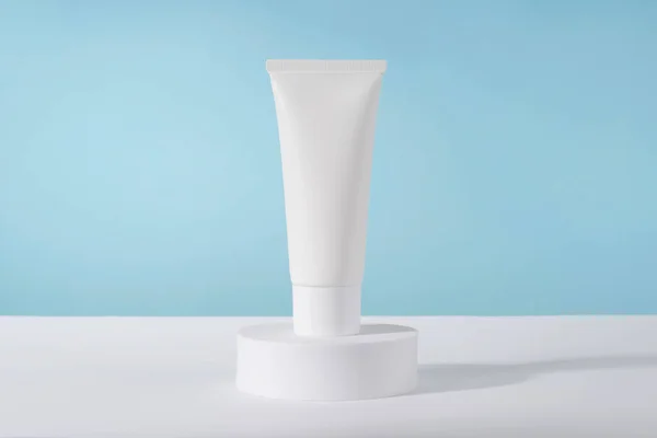 Cosmetic luxury cream tube bottle mockup on blue background on pedestal podium. Unbranded lotion beauty product packaging. Product presentation mock up. Lotion, mousse, cleanser for skincare routine
