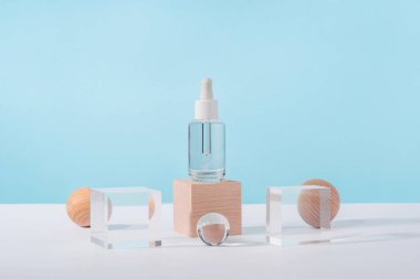 Pembe arka planda peptit ve retinol içeren serum kozmetik şişesi ve ahşap bloklar. Yağ kozmetik şeffaf ürün ambalajı ve şık dekorlar. Serum düşürücü, kaide podyumunda maket.
