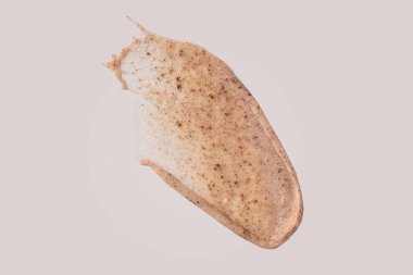 Bej arka planda izole edilmiş leke örneği. Pul pul dökülmüş krema lekesi. Aşındırıcı parçacık örneğiyle kozmetik cilt bakımı ürünü, nazik çıplak fırça dokusu izole.