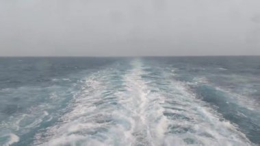 Parlak yaz gününde okyanusta gemi izleri var.