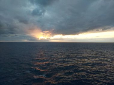 Altın gün batımı ve bulutlu gökyüzü, bir yolcu gemisinden manzara