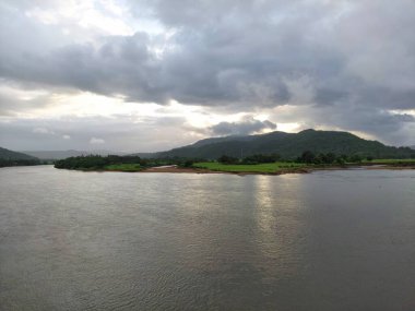 beautiful river near mountain under cloudy sky and a rice field