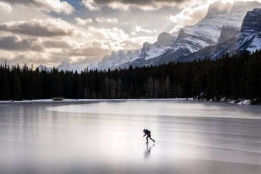 Banff Ulusal Parkı 'ndaki donmuş bir dağ gölünde buz pateni yapan biri.