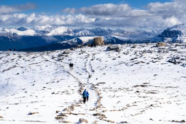 Jasper Ulusal Parkı Kanada 'da karla kaplı bir dağın tepesinde yürüyüş yapan turistler görülüyor.