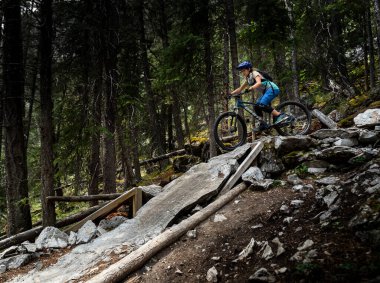 Banff Alberta Canada, Temmuz 04 2021: Genç bir kız dik kayalıklardan aşağı dağ bisikletine biniyor