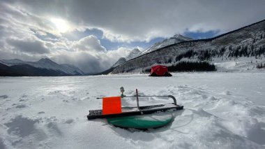 Canmore Alberta Canada, 31 Ocak 2022: Kanada Rocky Dağları 'ndaki Sprey Gölleri' nde buzda bir balıkçı oltası ve buz balıkçılığı çadırı kuruldu