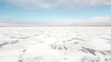 Alberta Kanada 'da güneşli bir günde donmuş bir göl ve tundra üzerinde alçak uçuş..