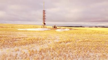 İzole edilmiş bir gaz kuyusunun Kuzey Amerika 'da bir sabah güneşinin altında toplanan buğday tarlasında havadan uçuşunu izlemek..