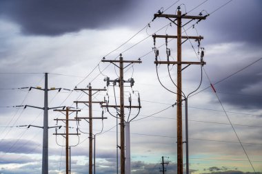Elektrik hatları Rocky View County Alberta Canada 'da bulutlu bir gökyüzünün altında tahta elektrik direklerinden ve çelik şanzıman kulelerinden sarkıyor..