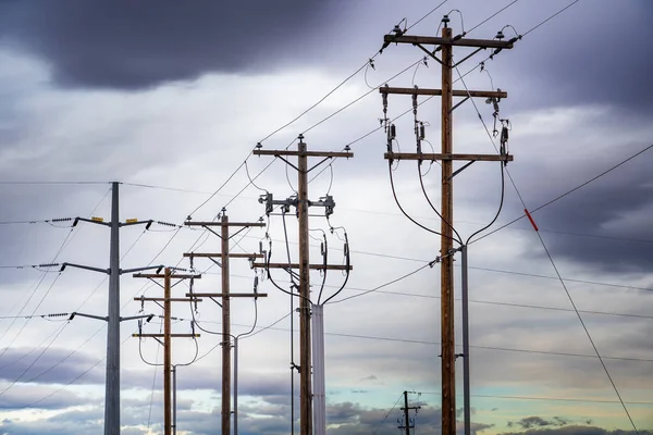 Stromleitungen Hängen Hölzernen Strommasten Und Stählernen Sendemasten Unter Einem Bewölkten — Stockfoto