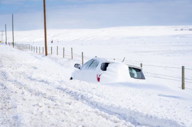 Rocky View County Alberta Canada, 20 Nisan 2022: Rekor bir kar yağışı sırasında kırsal bir yoldan kaydıktan sonra kara gömülen bir araba.