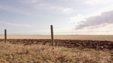 Rocky View County Alberta 'daki bir buğday tarlasında sürgülü bir patika ile Kanada bozkırlarında dikenli tel örgüler boyunca hareket ediyor..
