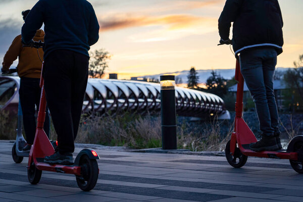 Калгари Альберта Канада, 16 мая 2022: Коммутеры ездят на электронном скутере рядом с мостом Мира с пешеходами в популярном центре города.