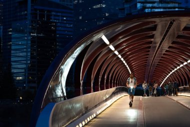 Calgary Alberta Canada, 16 Mayıs 2022: Hareket halindeki bir turist, yayalarla birlikte geceleyin Barış Köprüsü 'nden elektrikli scooter ile geçiyor.