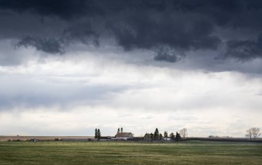 Rocky View County Alberta Canada 'da şiddetli bir hava olayı sırasında Kanada ovalarında bir kır evinin üzerinde dolu fırtınası oluşur..