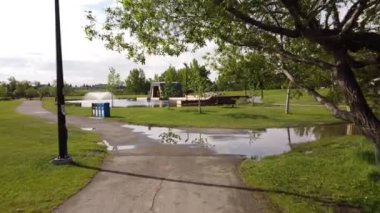 Airdrie Alberta Canada, Haziran 07 2022: Bir bisiklet yolu ve yağmur birikintileri üzerinde Nose Creek Parkı 'nda uzak bir alabalık havuzu olan hiç insan bulunmamaktadır..