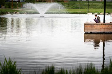Airdrie Alberta Canada, 16 Haziran 2022: Nose Creek Parkı 'ndaki gökkuşağı alabalık havuzunda olta tutan bir çocuk.