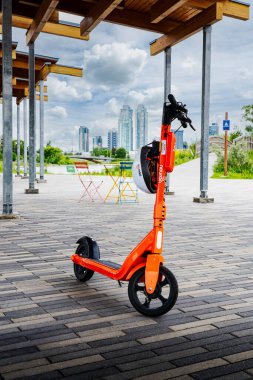 Calgary Alberta Canada, July 02 2022: A Neuron electric scooter parked under an outdoor shelter with patio furniture overlooking the downtown East Village and skyline.