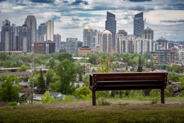 Calgary Alberta Canada, July 02 2022: A park bench with no people overlooking the downtown skyline and inner city homes.