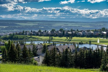 Cochrane Alberta Canada, July 14 2022: Overlooking a small Alberta town with the Glen Eagles Golf Course and distant Rocky Mountains.