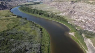 Aerial tilt revealing shot over the Red Deer River and Canadian Badlands during summer near Drumheller Alberta.
