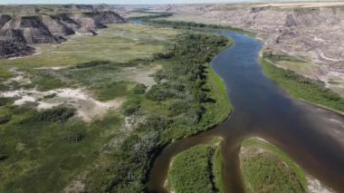 Aerial tilt revealing flight over the Red Deer River and the Alberta Badlands during summer.