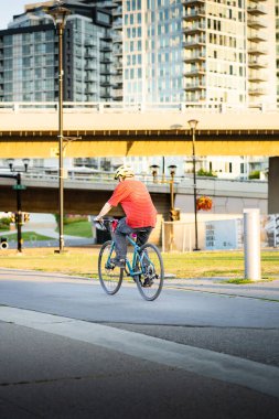 Calgary Alberta Canada, July 27 2022: A person riding their bicycle along a pedestrian pathway with background  buildings near the downtown East Village.