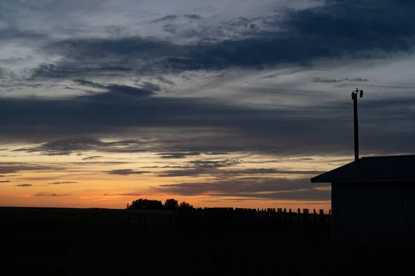 Country home sunset silhouette scene on the Alberta prairies in Rocky View County