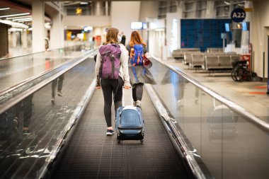 Calgary Alberta Canada, Eylül 08 2022: Gezgin Uluslararası Havalimanı 'ndaki terminalleri değiştirirken güçlü bir yatay yürüyen merdiven boyunca bavulunu çekiyor.