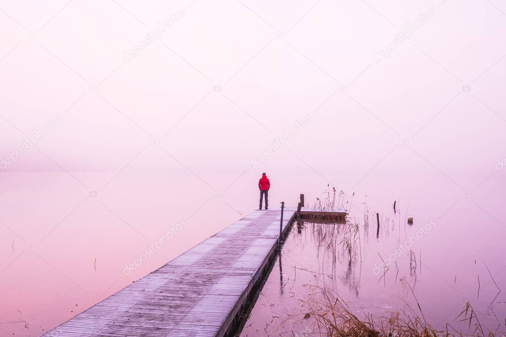 Man standing on jetty in mist