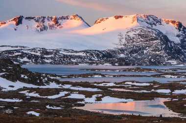 Karla kaplı dağlarda gün batımı ışığı