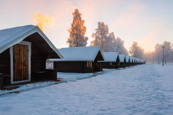 日出时分 一排排被雪覆盖的小木屋 — 图库照片