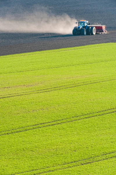 Traktör tarlada toprak sürüyor.