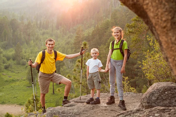 Pappa och två barn med ryggsäckar på vacker natur — Stockfoto