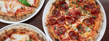 Yatay pankart ya da başlık Masada üç lezzetli İtalyan pizzası.