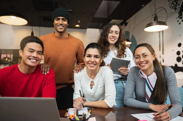 Kameraya gülümseyen beş genç insanın olduğu çok ırklı bir grup..