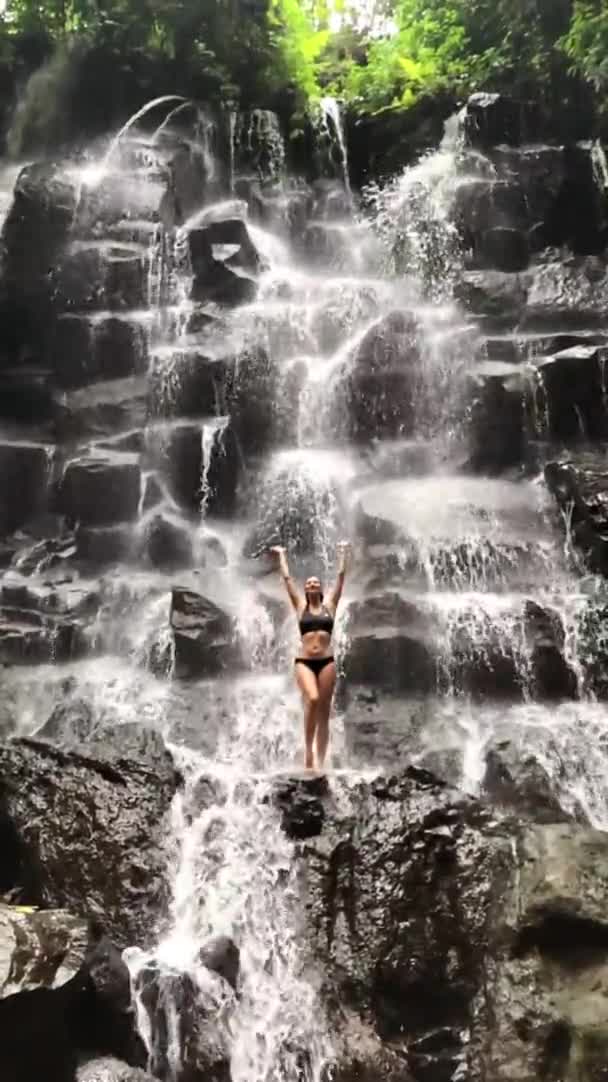 Piękna kobieta z pięknym ciałem stojąca na skale pod wodospadem Kanto Lampo Bali — Wideo stockowe