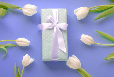 Günümüzde ve çiçeklerde beyaz laleler var. Kadınlar gününde. Anneler Günü. Çiçekler. Beyaz kurdeleli bir hediye..