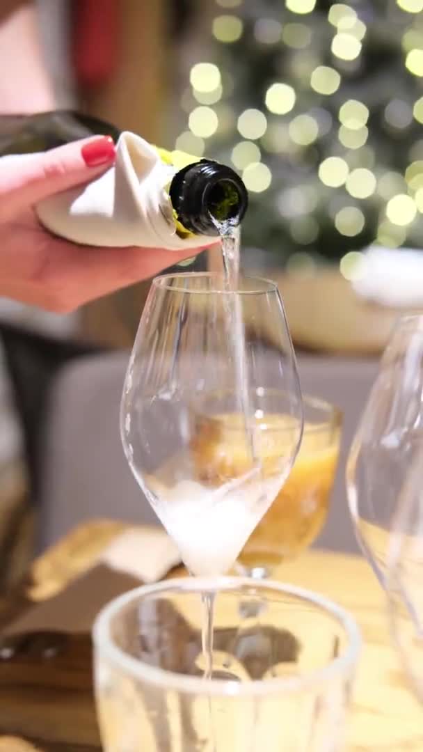 Copo de champanhe 4k perto de árvore de Natal bokeh ouro. Feminino Despeje a bebida em um copo. . — Vídeo de Stock