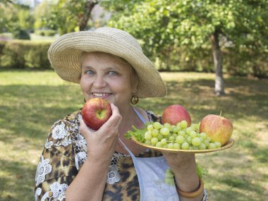 ülkede elma ve üzüm ile gülümseyen yaşlı kadın