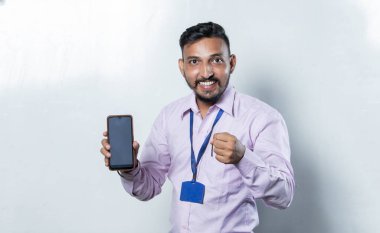 Hintli adam elinde telefonla pozitif tavır sergiliyor.