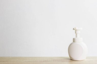 Beyaz plastik şişe, arka planda sabun makinesi var..