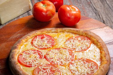Napoli Brezilya pizzası mozzarella peyniri, domates dilimleri, kekik peynirli parmesan peyniri ahşap arka planda, Brezilya 'da buna pizza Napolitana denir..