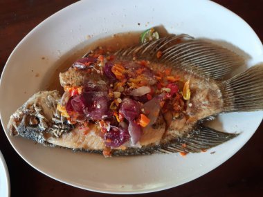 Sebzeli ve soslu sazan balığı. Ahşap zemin üzerinde biberli ve soğanlı sazan balığı. Üst 