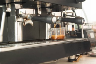 Kahve yaparken büyük kahve makinesi ve siyah kupa. Küçük işletme kavramı.