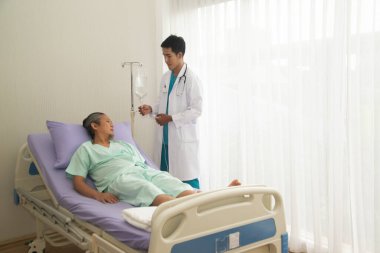 Asyalı erkek doktor, yaşlı Asyalı erkek hastayı hastanede muayene ediyordu.. 